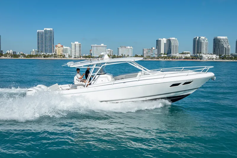 Slide: The Image of 2016 Intrepid 375 Center Console cruising on blue water with city skyline backdrop. - 15
