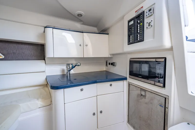 Slide: The Image of 2016 Intrepid 375 Center Console interior with kitchenette, featuring sink, microwave, and control panel. - 25