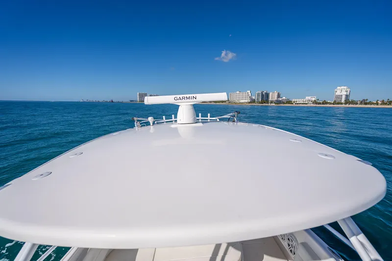 Slide: The Image of 2016 Intrepid 375 Center Console boat cruising near a coastal city skyline. - 57