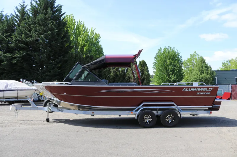 The Image of 2026 Alumaweld Intruder 22 boat on trailer, parked outdoors with trees in background. - 1