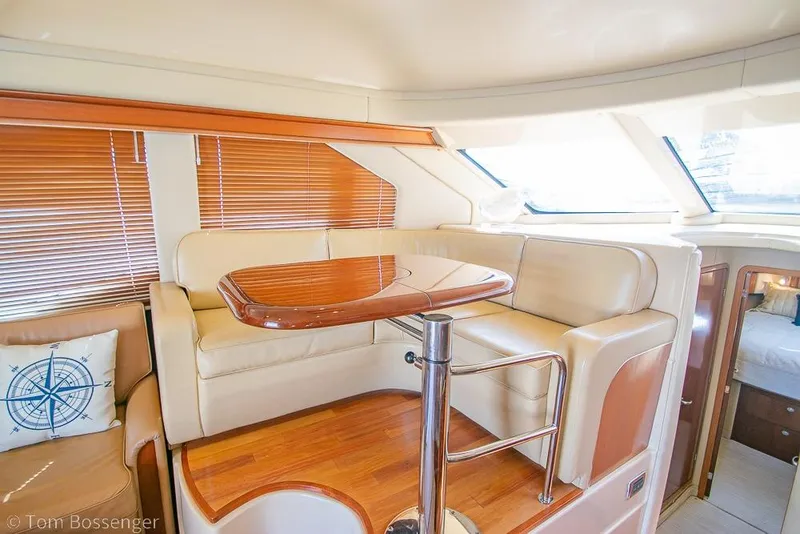 Slide: The Image of Luxurious interior of 2005 Sea Ray 420 Sedan Bridge yacht with leather seating and wooden table. - 11