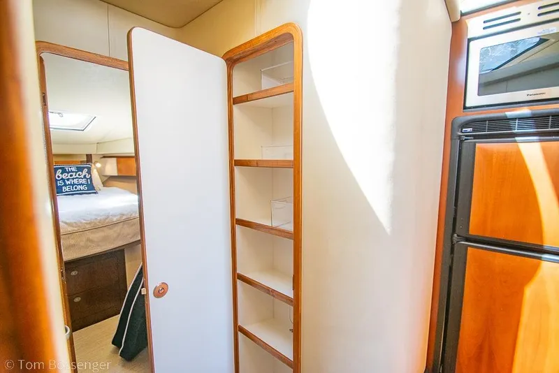 Slide: The Image of Interior of 2005 Sea Ray 420 Sedan Bridge with open shelving and cozy bedroom view. - 27