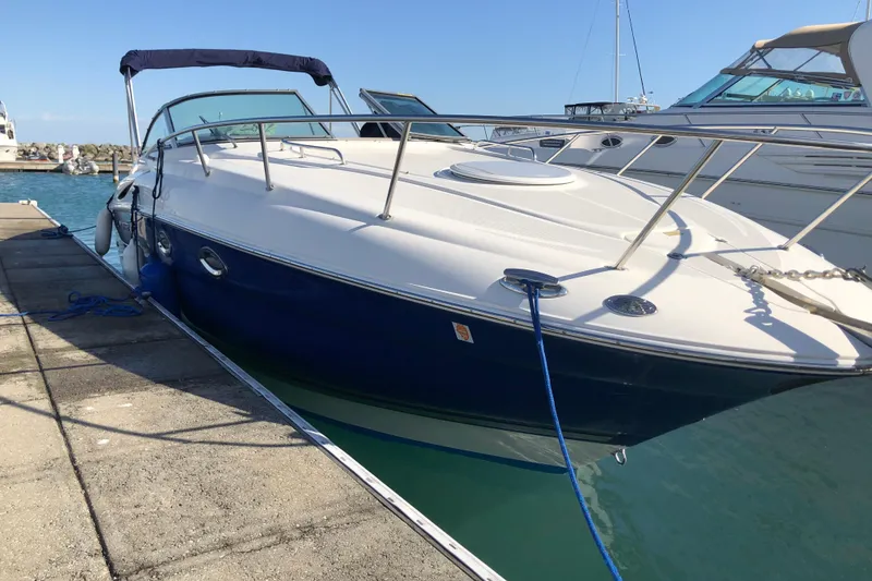 The Image of 2006 Monterey 250 Cruiser docked at marina, featuring sleek design and blue hull. - 0