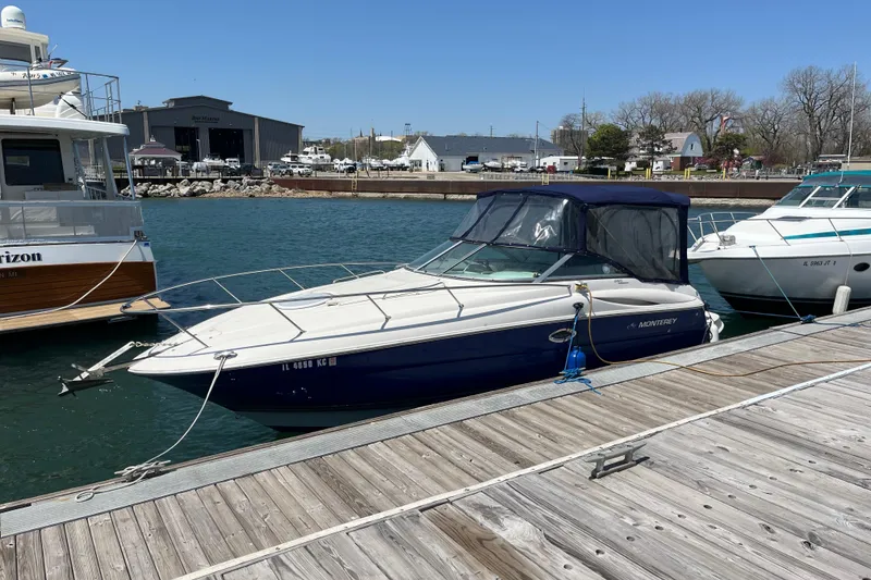 Slide: The Image of 2006 Monterey 250 Cruiser docked at a marina, surrounded by other boats. - 2