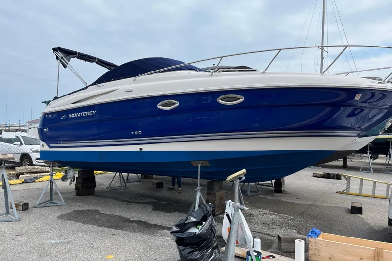 Slide: The Image of 2006 Monterey 250 Cruiser boat in dry dock, blue and white hull, marina background. - 4
