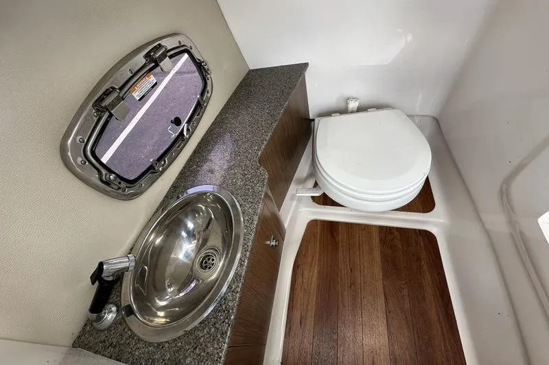 Slide: The Image of 2015 Chaparral 257 SSX boat bathroom with sink, toilet, and wood flooring. - 16