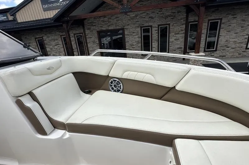 Slide: The Image of 2015 Chaparral 257 SSX boat interior with white and brown seating, near a stone building. - 27