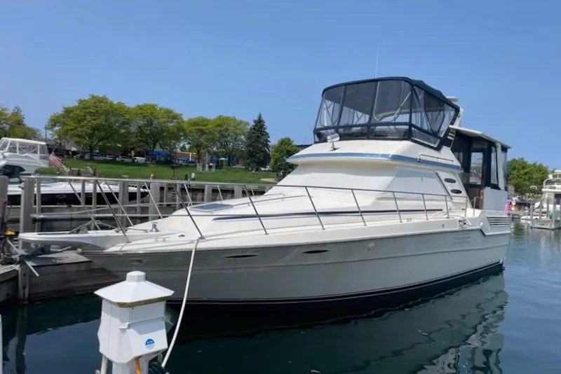 The Image of 1987 Sea Ray 410 Aft Cabin yacht docked at marina, clear sky, calm water. - 0