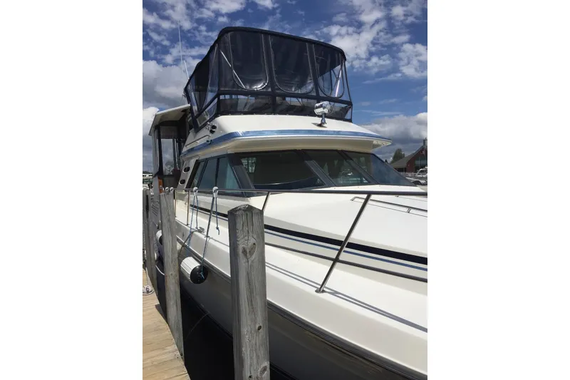 Slide: The Image of 1987 Sea Ray 410 Aft Cabin yacht docked under a partly cloudy sky. - 3