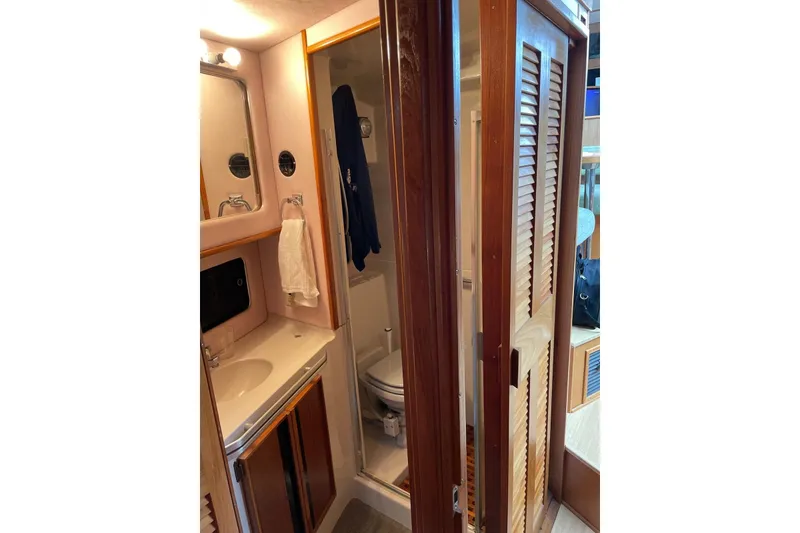 Slide: The Image of 1987 Sea Ray 410 Aft Cabin bathroom with sink, mirror, and wooden cabinetry. - 7