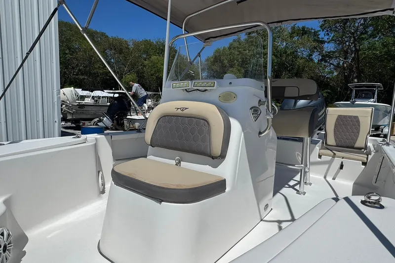 Slide: The Image of 2018 Tidewater 1910 Bay Max boat interior with seating and console, parked outdoors. - 2