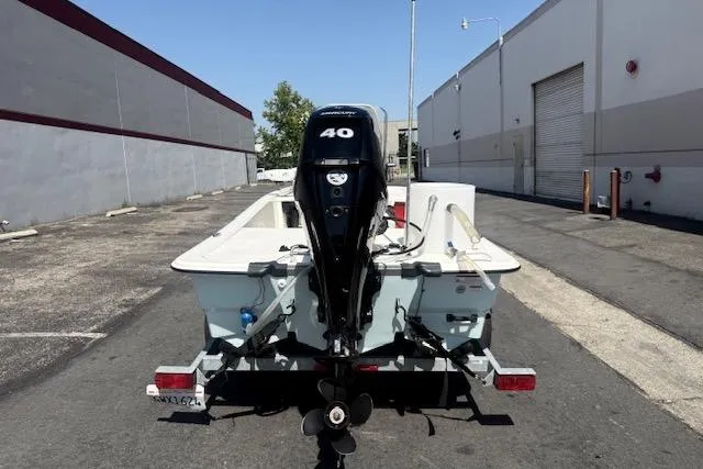 Slide: The Image of 2024 Mako Pro Skiff 13 CC boat with 40 HP engine on trailer, parked in urban area. - 12