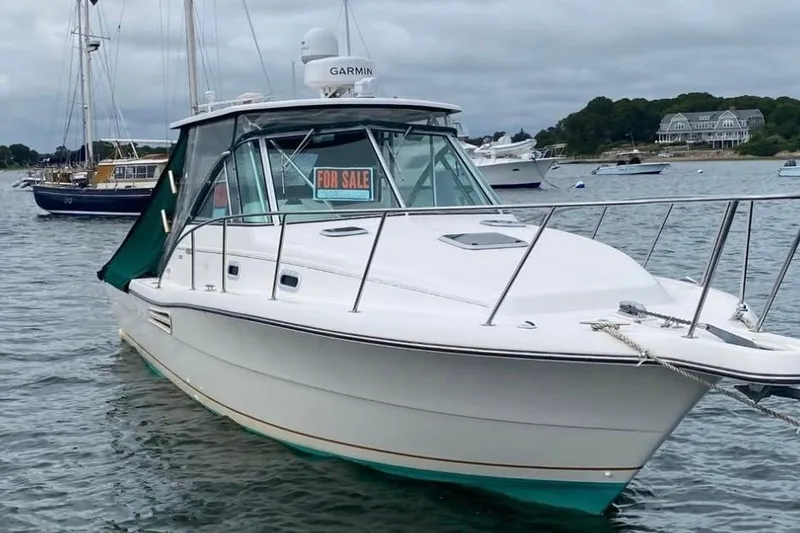 Slide: The Image of 2001 Pursuit 3000 Express boat with "For Sale" sign, anchored in a scenic harbor. - 4