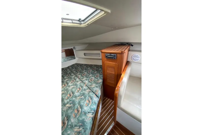 Slide: The Image of Interior cabin of 2001 Pursuit 3000 Express boat with patterned bedding and wooden accents. - 9