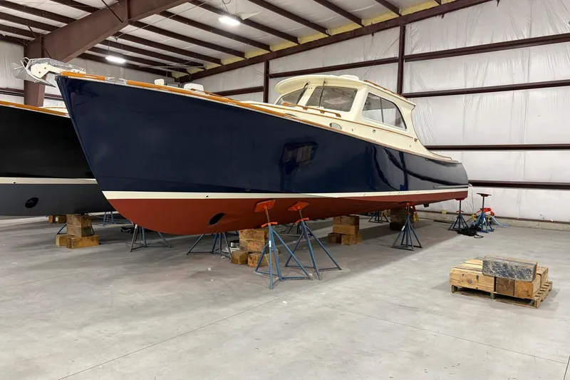 The Image of 2003 Hinckley Picnic Boat 36 EP in storage, blue hull, indoor facility. - 1