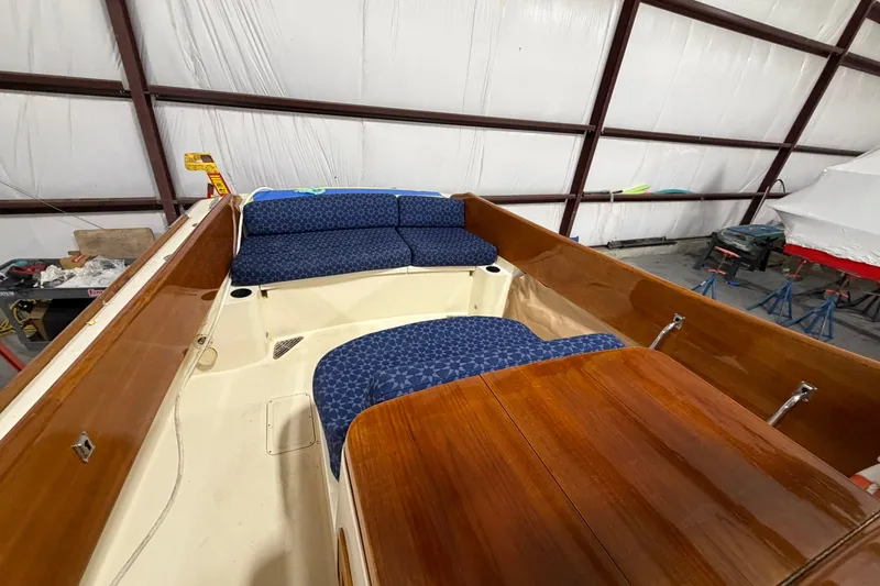 Slide: The Image of 2003 Hinckley Picnic Boat 36 EP interior with blue seating and wooden accents in a storage facility. - 8