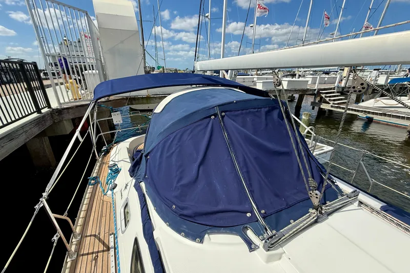 Slide: The Image of 2004 Jeanneau Sun Odyssey 35 sailboat docked, featuring blue canvas cover and wooden deck. - 16