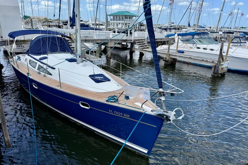 Slide: The Image of 2004 Jeanneau Sun Odyssey 35 sailboat docked at marina, blue hull, wooden deck. - 3