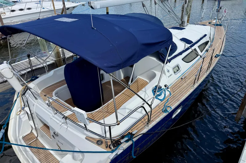 Slide: The Image of 2004 Jeanneau Sun Odyssey 35 sailboat docked with blue canopy and wooden deck. - 4