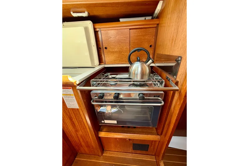 Slide: The Image of Compact kitchen area in a 2004 Jeanneau Sun Odyssey 35 sailboat with stove and kettle. - 48