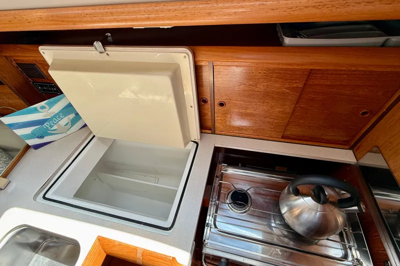 Slide: The Image of Galley of 2004 Jeanneau Sun Odyssey 35 with open storage and stainless steel kettle. - 49