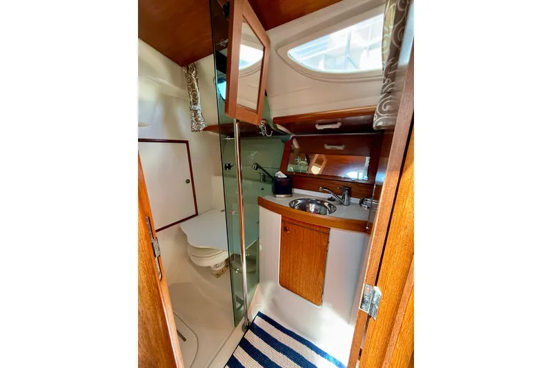 Slide: The Image of 2004 Jeanneau Sun Odyssey 35 yacht bathroom with sink, mirror, and wooden cabinetry. - 57