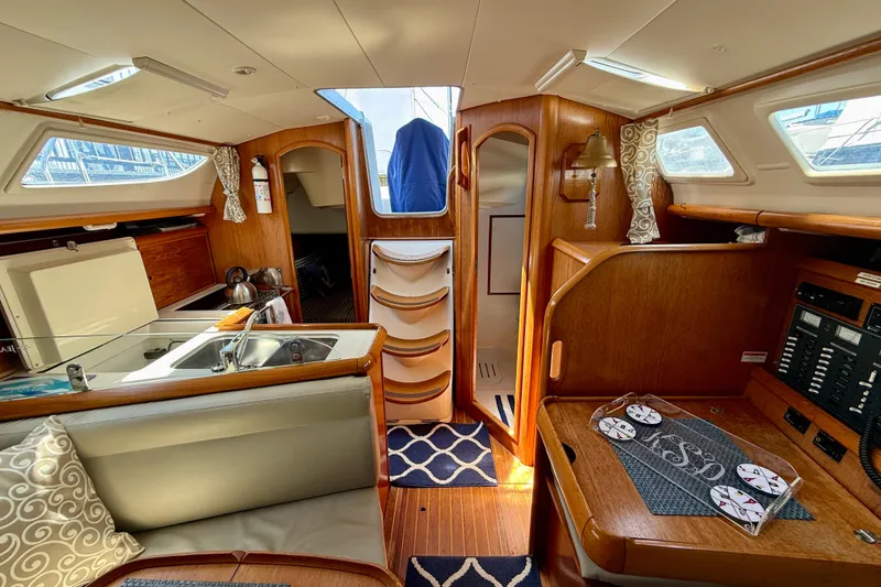 Slide: The Image of Interior of 2004 Jeanneau Sun Odyssey 35 sailboat, featuring cozy wood finish and compact kitchen area. - 80