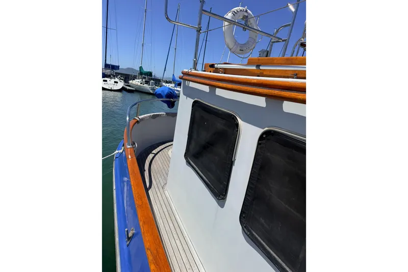 Slide: The Image of 1987 Lord Nelson Victory Tug boat docked, featuring wooden railings and black window covers. - 10