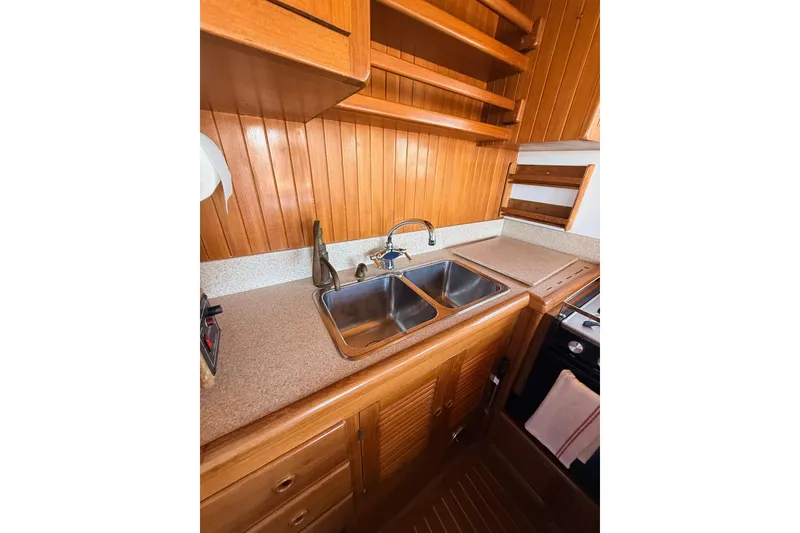 Slide: The Image of Wood-paneled kitchen in 1987 Lord Nelson Victory Tug, featuring double sink and shelving. - 26