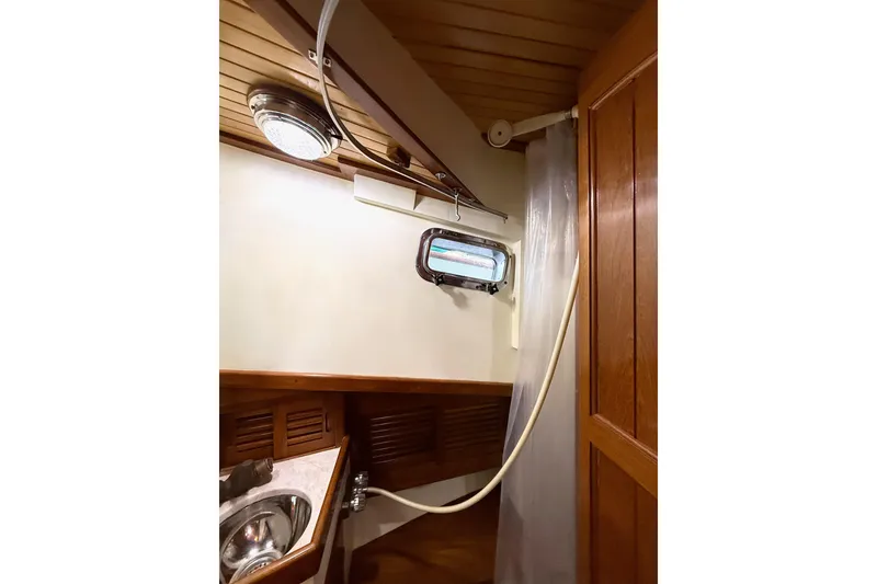 Slide: The Image of Interior of 1987 Lord Nelson Victory Tug bathroom with sink, shower, and porthole window. - 40