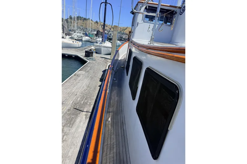 Slide: The Image of 1987 Lord Nelson Victory Tug docked at marina, showcasing side view and wooden railings. - 5