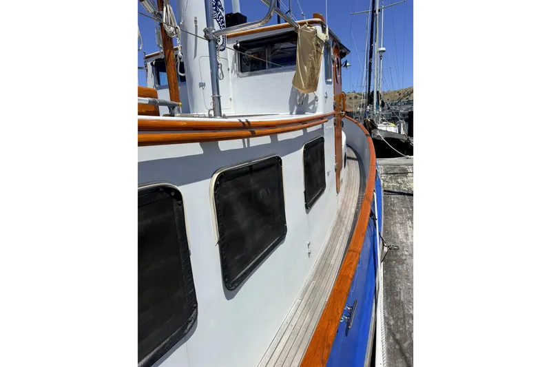 Slide: The Image of 1987 Lord Nelson Victory Tug boat with wooden railings and windows docked at a marina. - 9