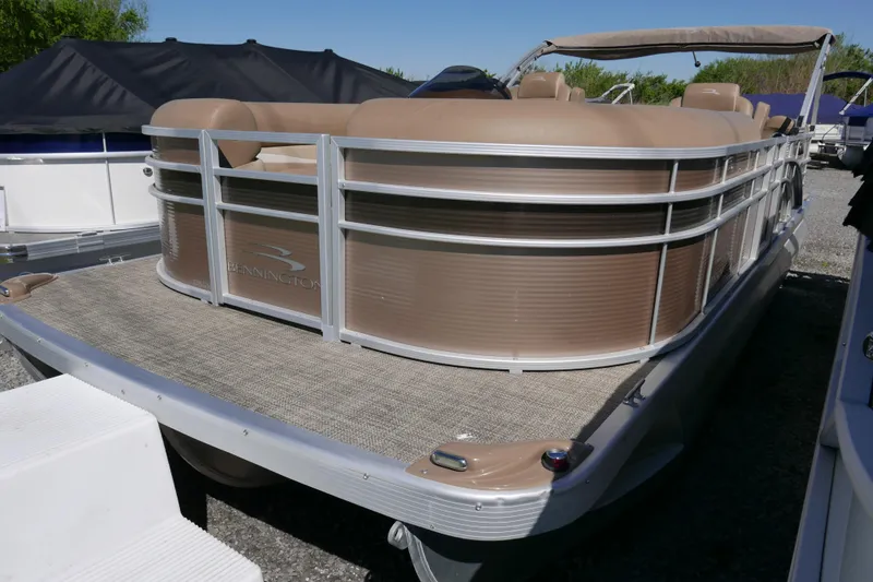 The Image of 2016 Bennington 2250GSR pontoon boat with beige seating and canopy, docked outdoors. - 0