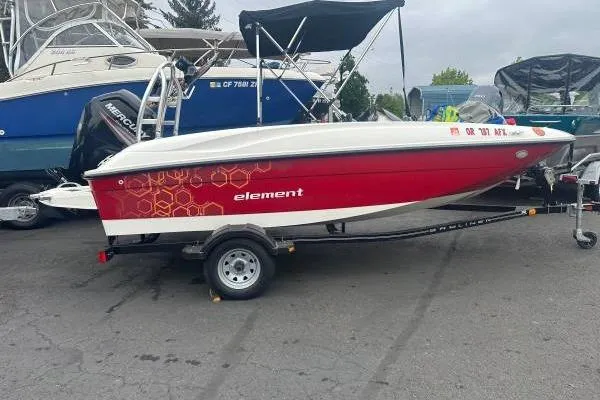 The Image of 2016 Bayliner 160 Element boat with red hull on trailer, parked outdoors. - 1