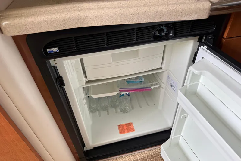 Slide: The Image of Open mini fridge inside 2004 Wellcraft 330 Coastal boat, containing water bottles and a plastic bag. - 15