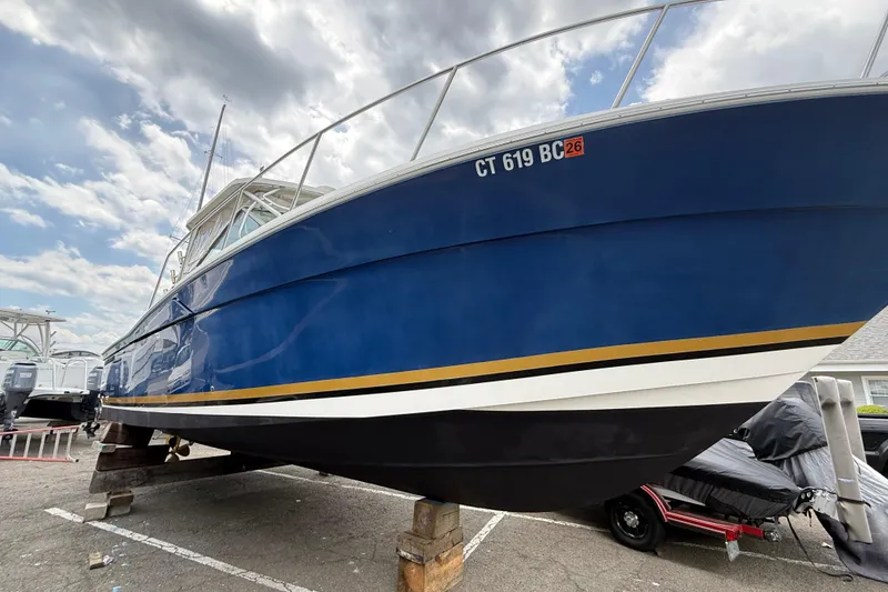 Slide: The Image of 2004 Wellcraft 330 Coastal boat on dry dock under cloudy sky. - 2