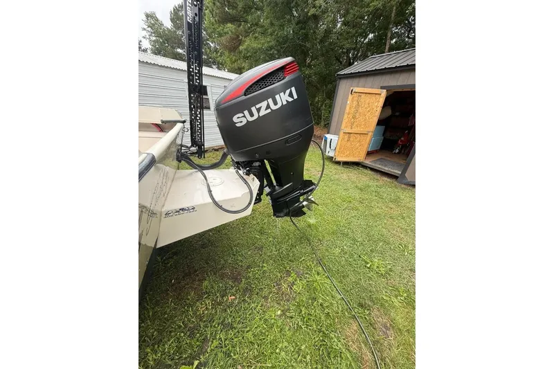 Slide: The Image of 1981 Grady-White boat with Suzuki outboard motor, parked on grass near a shed. - 4
