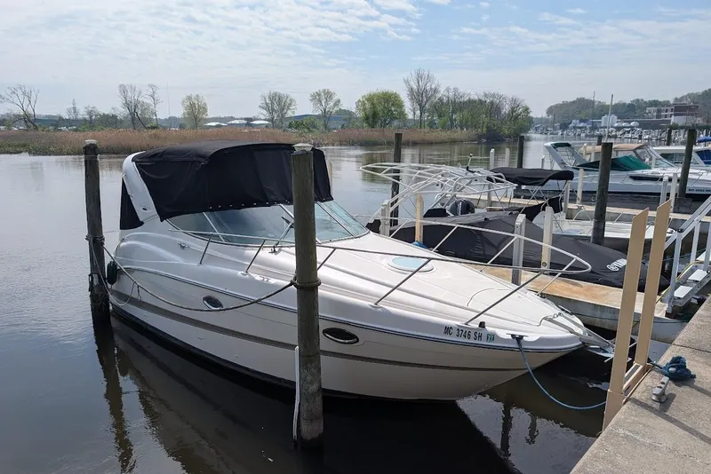 The Image of 2002 Maxum 2700 SCR boat docked at a marina, featuring a black canopy. - 0