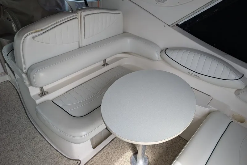 Slide: The Image of Interior seating area of 2002 Maxum 2700 SCR boat with round table and cushioned seats. - 13