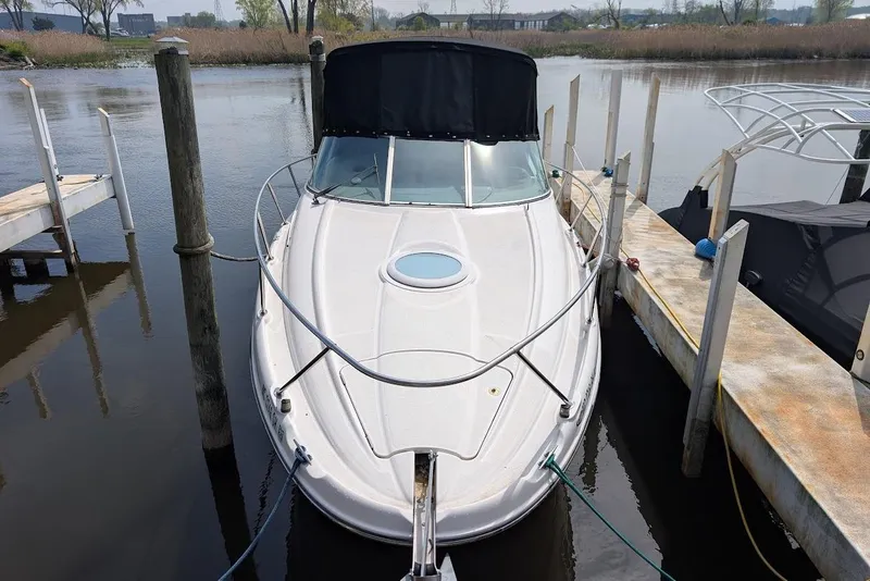 Slide: The Image of 2002 Maxum 2700 SCR boat docked in a marina, featuring a sleek white design. - 2