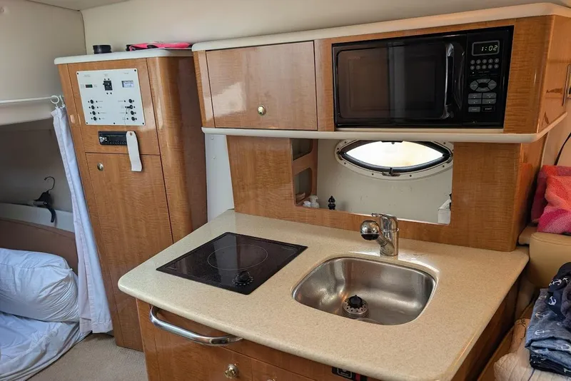 Slide: The Image of Compact kitchen area in a 2002 Maxum 2700 SCR boat with microwave and sink. - 29