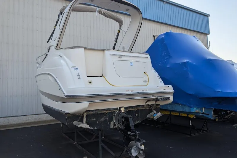 Slide: The Image of 2002 Maxum 2700 SCR boat on stands, rear view, next to a covered vessel. - 45