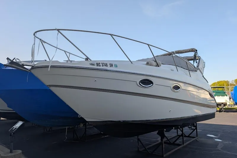 Slide: The Image of 2002 Maxum 2700 SCR boat on stands, white hull, docked outdoors. - 47