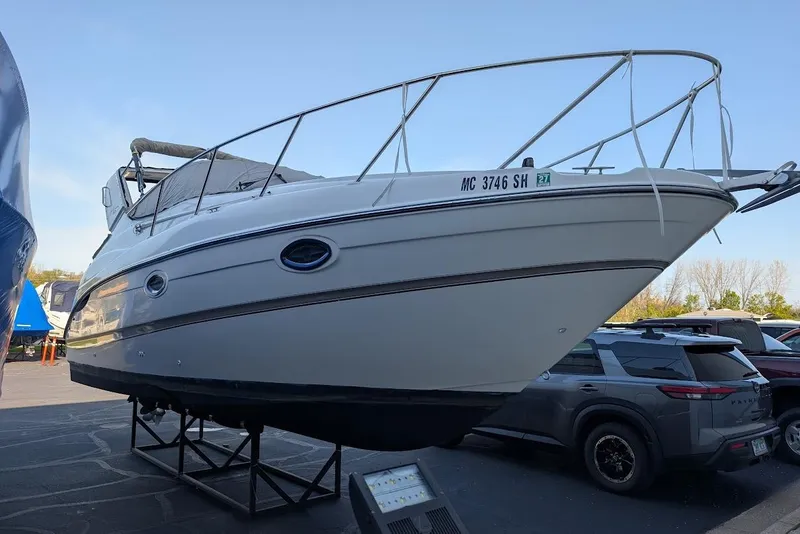 Slide: The Image of 2002 Maxum 2700 SCR boat on display, elevated on stands in a parking area. - 48