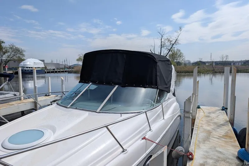 Slide: The Image of 2002 Maxum 2700 SCR boat docked by a calm waterfront under a clear sky. - 5