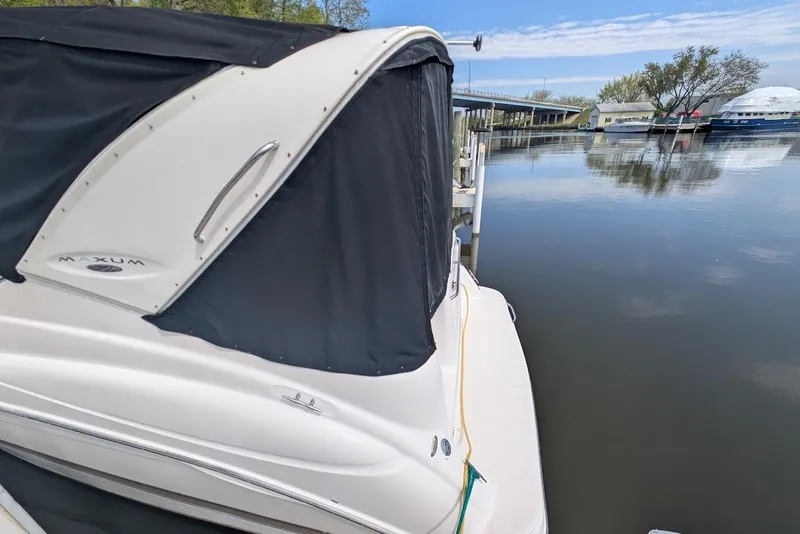 Slide: The Image of 2002 Maxum 2700 SCR boat docked on calm water with black canopy. - 8
