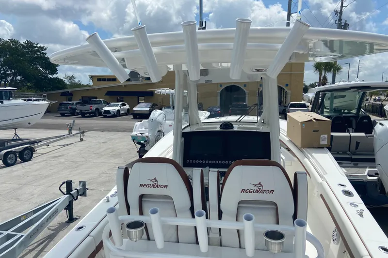 Slide: The Image of 2026 Regulator 28 boat with dual seats and rod holders, parked at a marina. - 18
