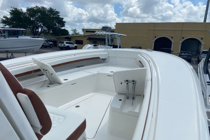 Slide: The Image of 2026 Regulator 28 boat with sleek white deck and brown seating, parked outdoors. - 25