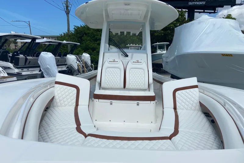 Slide: The Image of 2026 Regulator 28 boat with luxurious white and brown seating, docked outdoors. - 28
