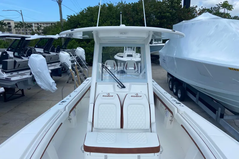 Slide: The Image of 2026 Regulator 28 boat with white seating and console, docked among other boats. - 29